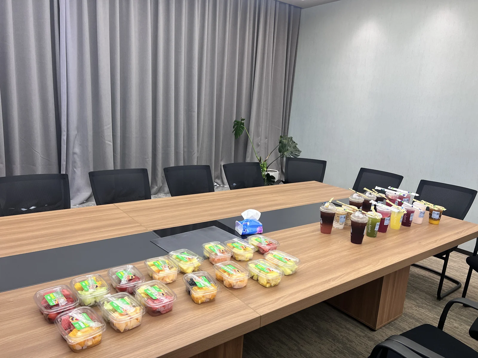会议桌上摆放着盒装水果、饮品和纸巾